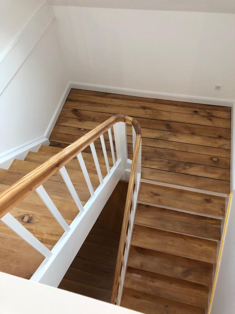 Eichen-Holztreppe mit weißem Stäbe-Geländer und Holz-Wandverkleidung